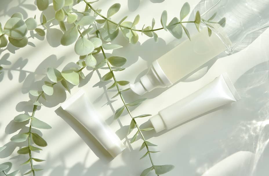 グリーンリーフとナチュラルな化粧品チューブのフラットレイ